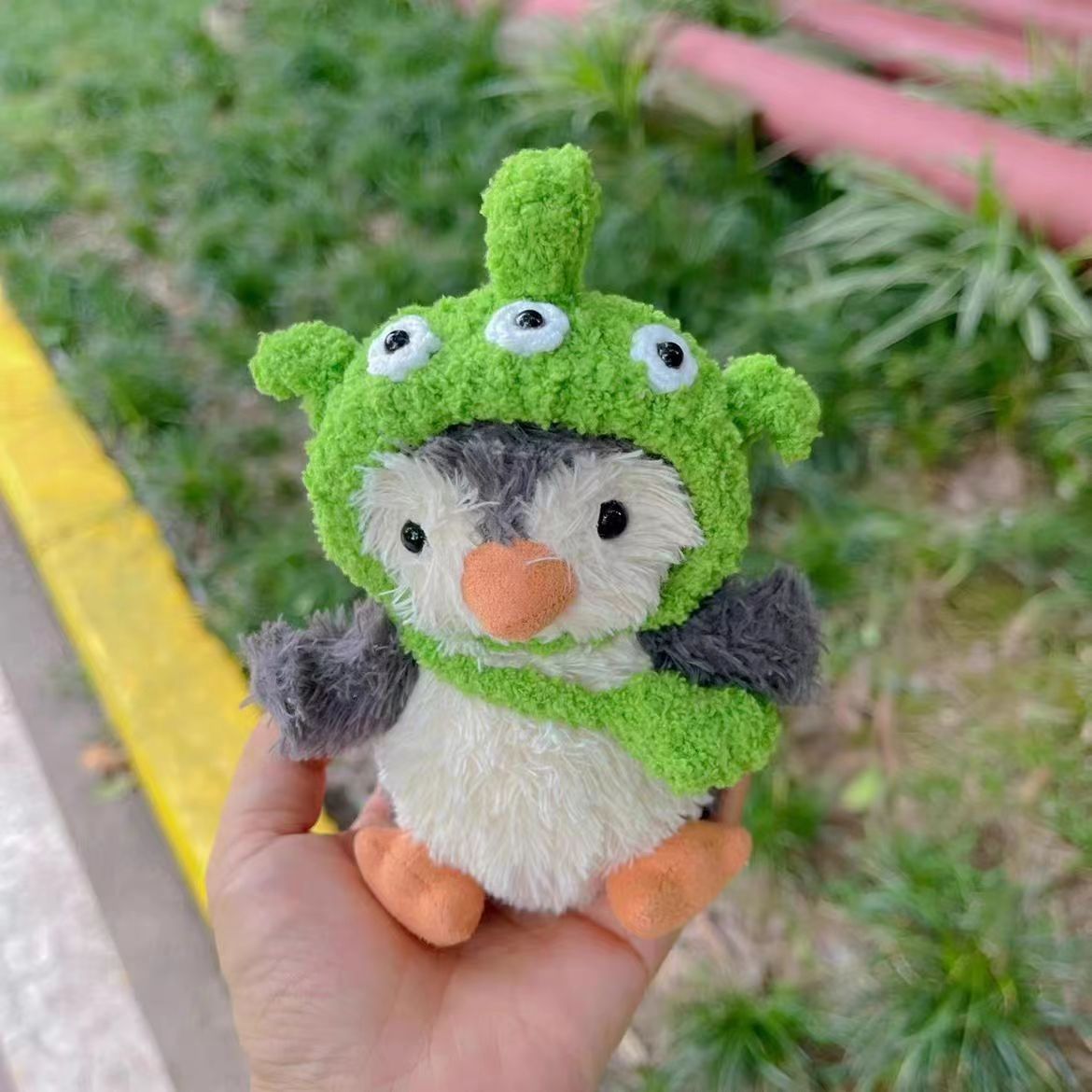 Alien Hat Outfit on 15cm plush penguin: vibrant lime green hand-crocheted alien hat with three protruding googly eyes, snu...