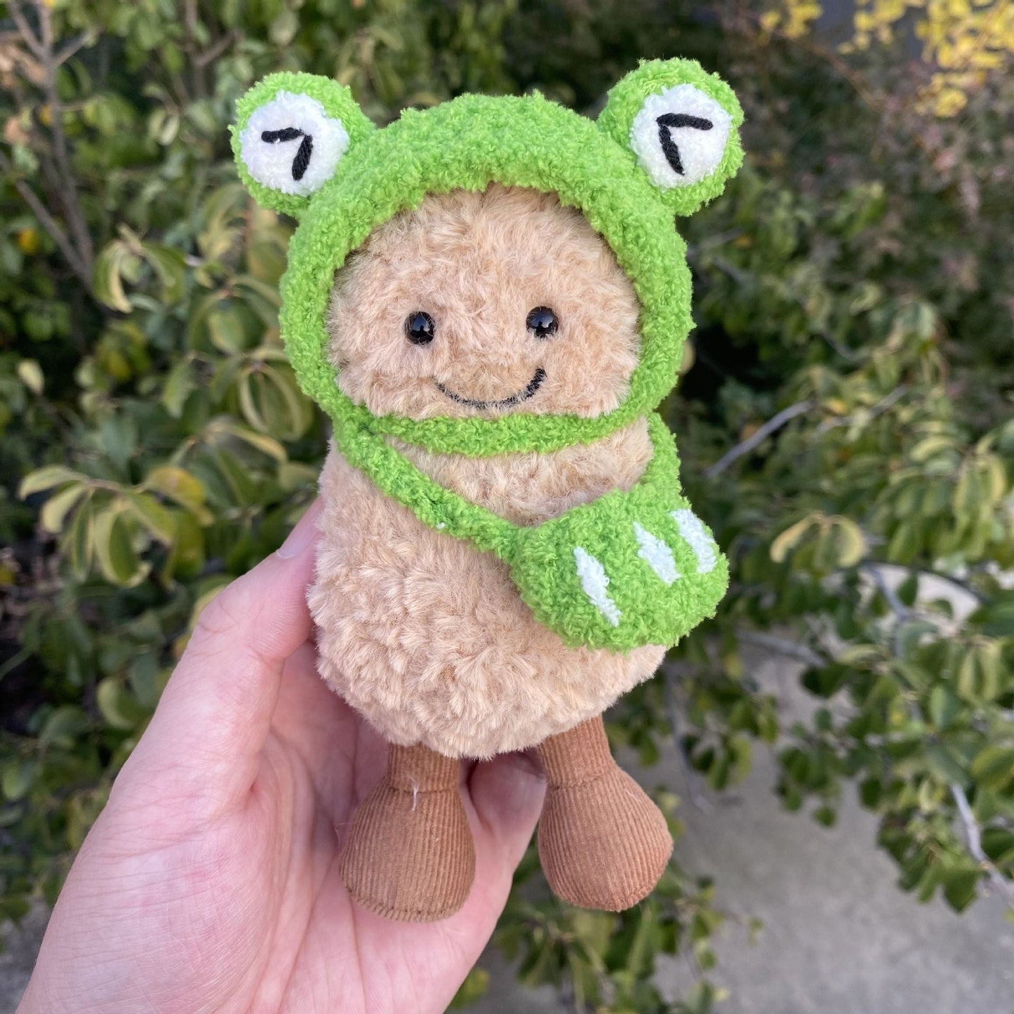 Frog Hat Scarf on 15cm plush doll: vibrant green hand-crocheted frog hat with protruding white-and-black eyes, matching gr...